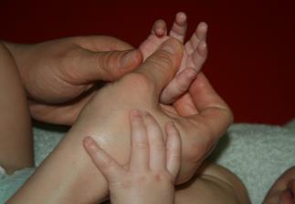Photo des mains d'un bébé massées par un parent pour stimuler son bien-être et sa motricité